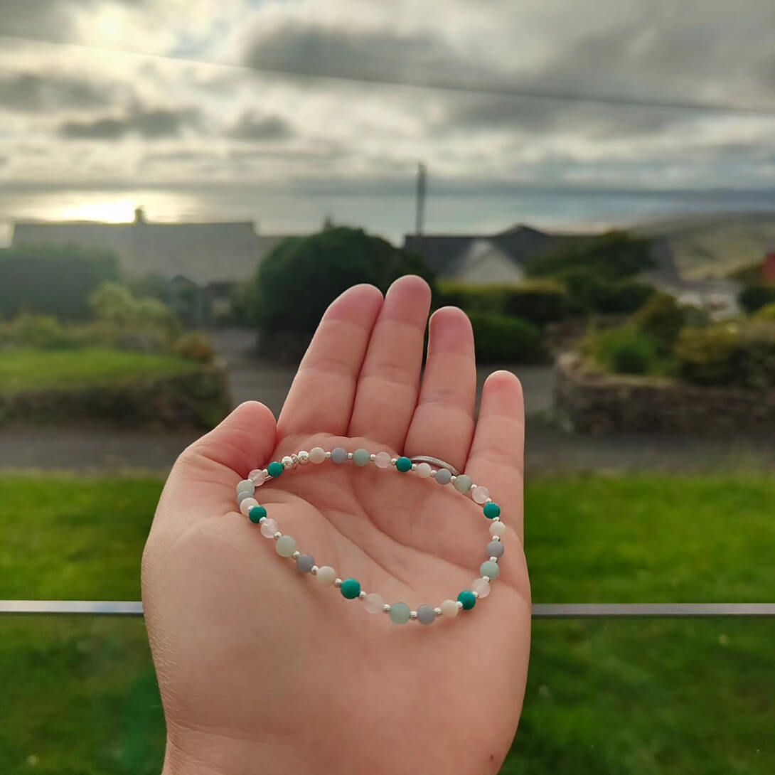 A hand holding a create your own bracelet
