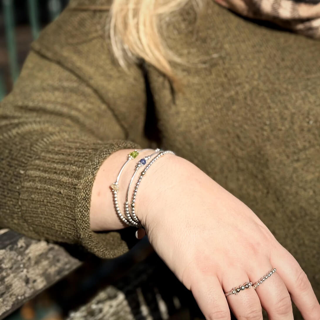 Three silver bracelets on a womans arm