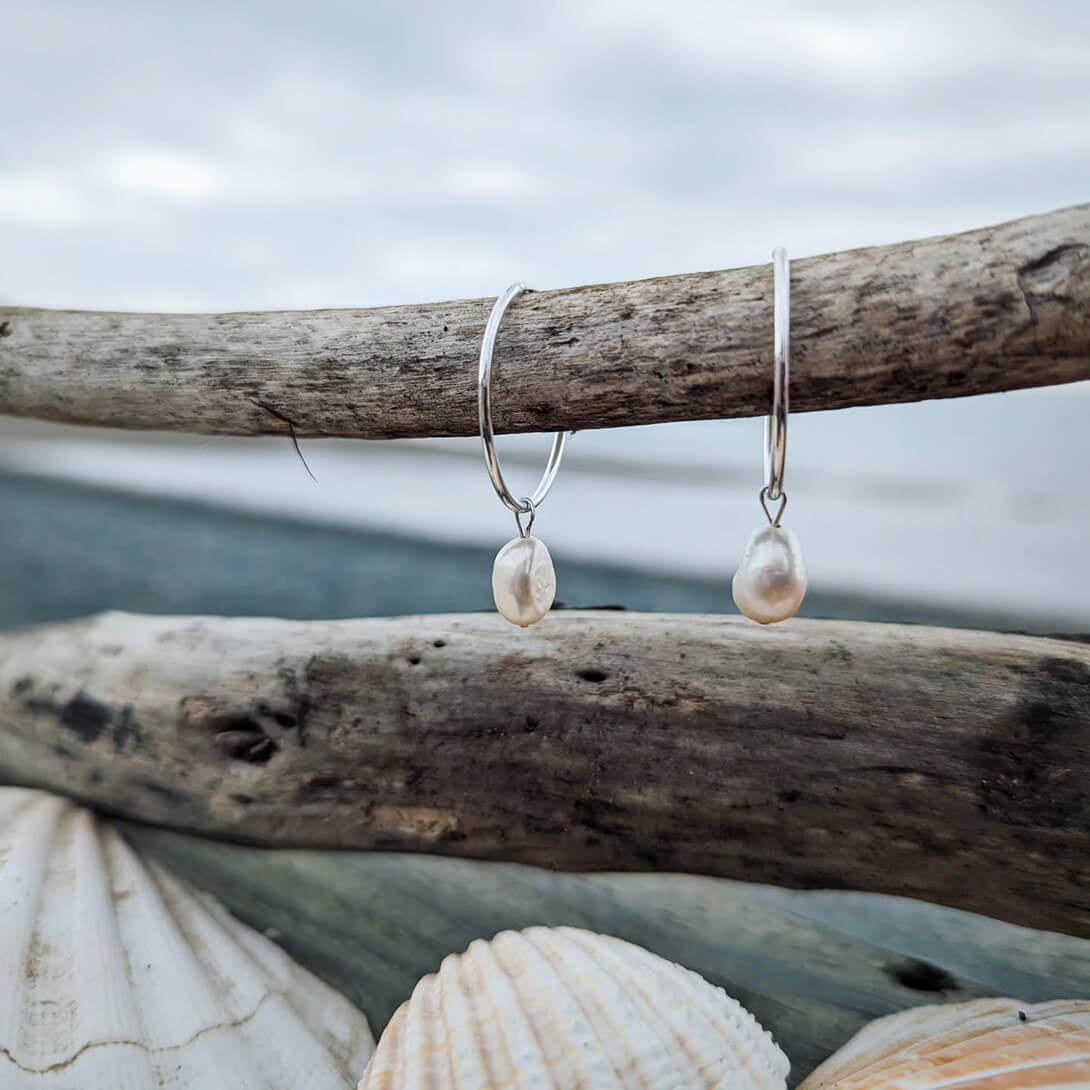 Pearl earrings hanginig on driftwood