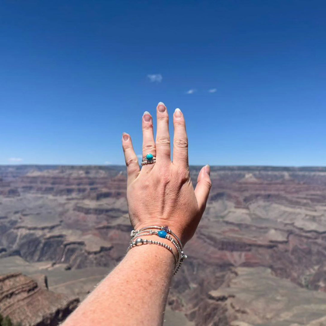A lady holding her hand out wearing a Sterling Silver ring in front of the Grand Canyon National Park