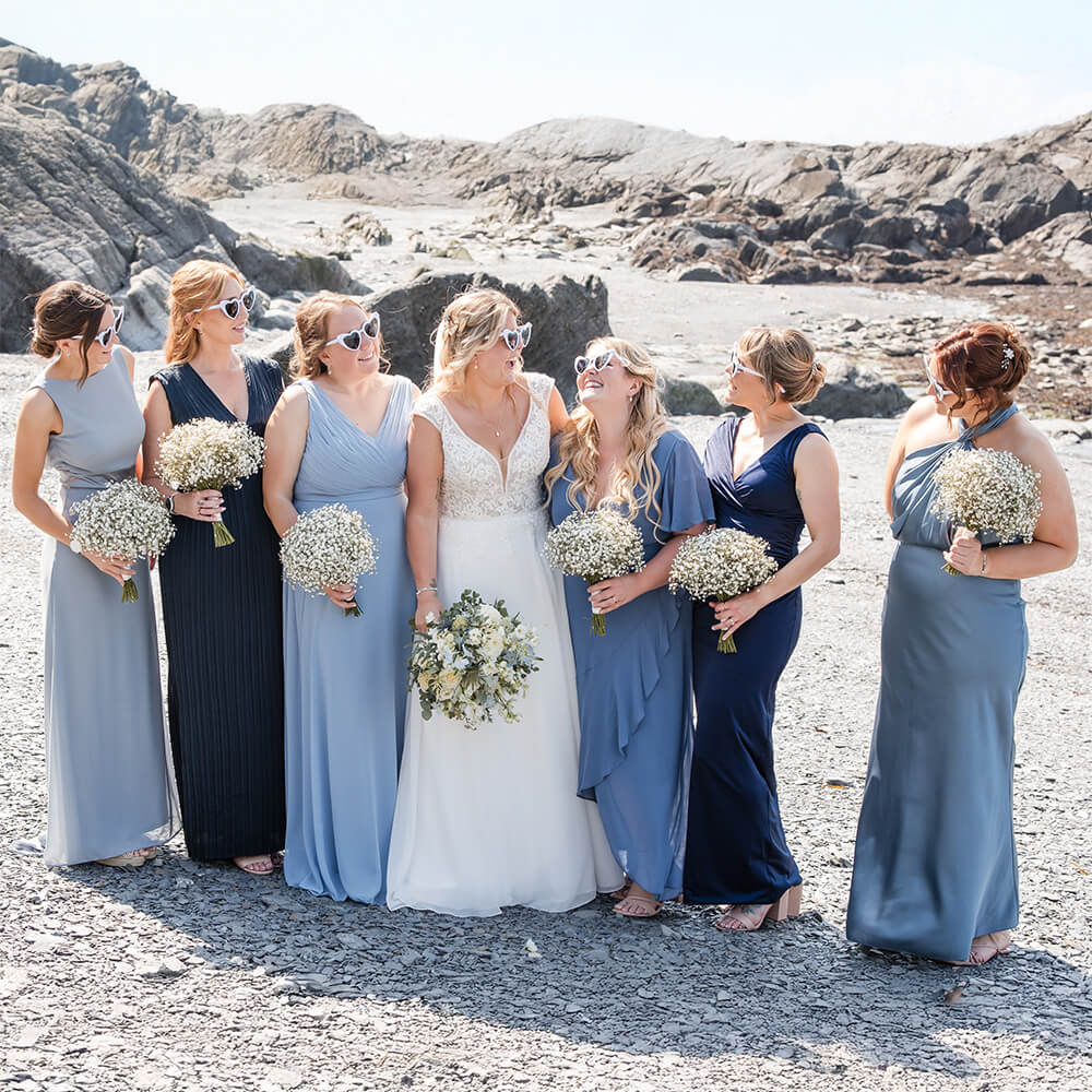 Bride with bridesmaids on a rocky beach