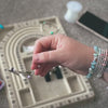 Lucy threading gemstones and closing a bracelet at her bead board